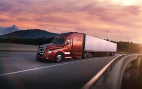 Freightliner Cascadia for regional distribution in red traveling on a highway with a scenic sunset background