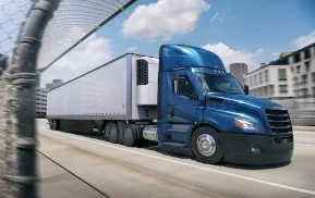 Freightliner Cascadia temperature-controlled reefer truck in blue driving in an urban setting