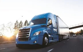 Freightliner Cascadia truck load/less than truck load model in bright blue driving on a road during dusk