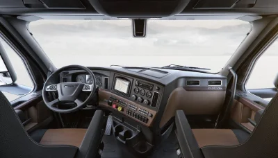 Driver's perspective inside Freightliner Cascadia cab with view of the dashboard, steering wheel, and front window