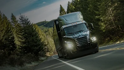 Freightliner eCascadia truck driving through a forested mountain road