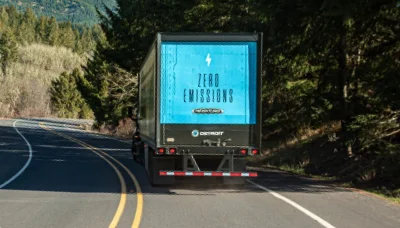 Rear view of Freightliner eCascadia truck with 'Zero Emissions' signage on highway amidst trees
