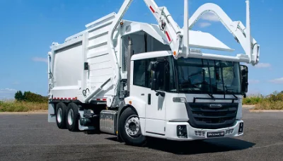 Freightliner econicSD garbage truck with extended hydraulic arm on a clear day