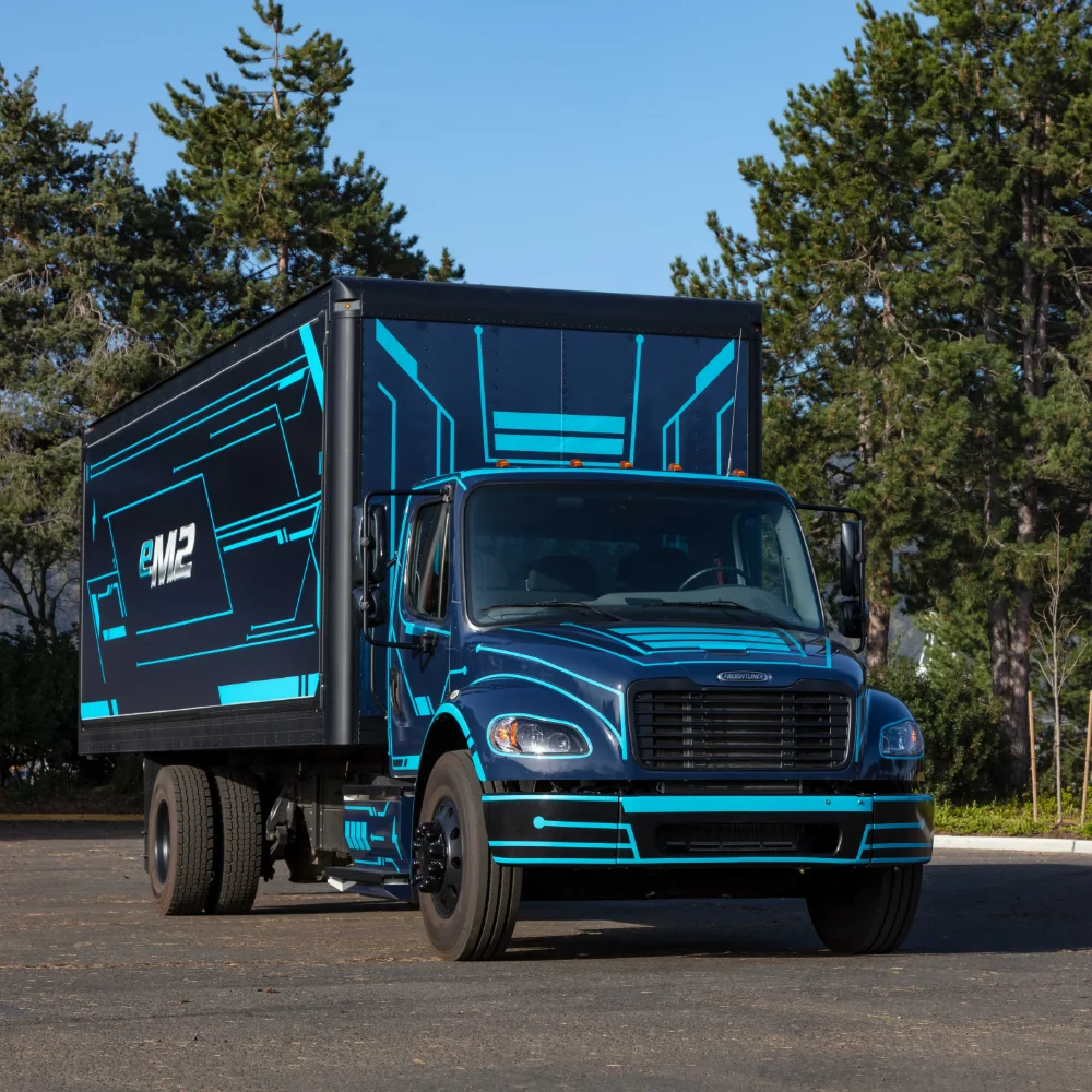 Dynamic shot of Freightliner eM2 electric truck with illuminated blue details against a dark studio background