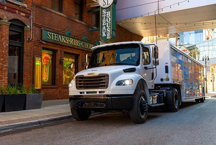 Freightliner M2 106 parked in an urban setting outside a steakhouse restaurant with ambient lighting