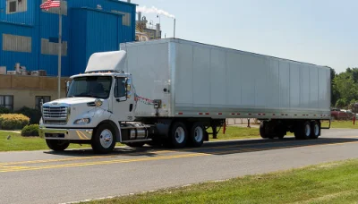 Freightliner M2 112 with attached trailer in front of industrial building