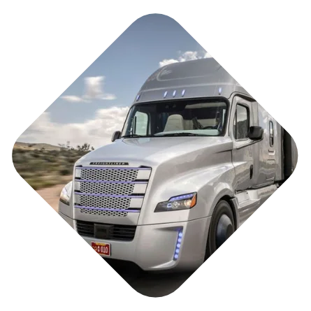 Triangular framed image of a silver Freightliner Cascadia truck driving on a desert road.