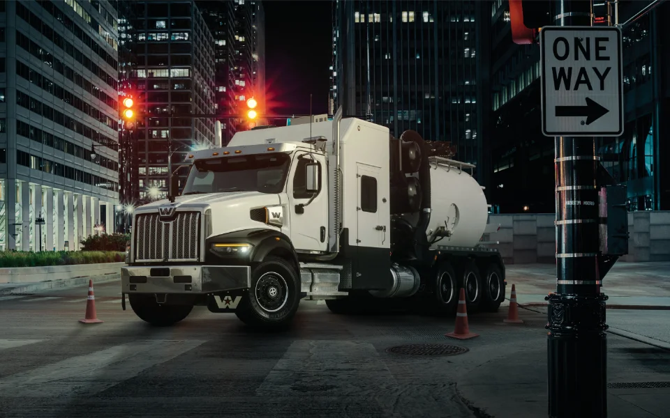 White Western Star 49x truck with a tanker trailer parked in a city street at night with tall buildings and 'one way' sign, Ottawa Ontario dealership